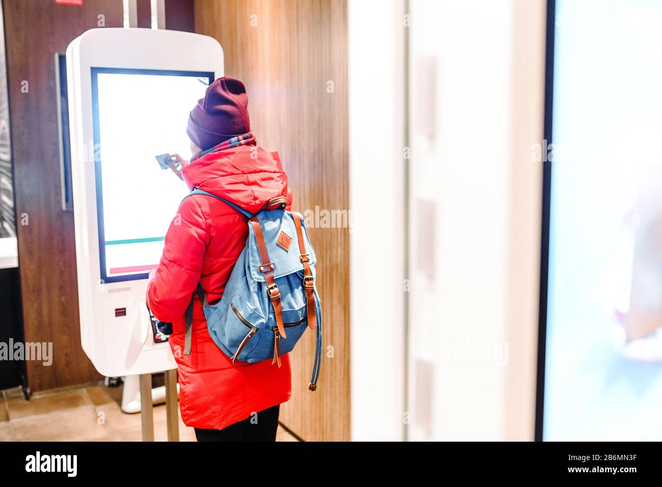 Una donna ordina un pasto nel terminale touch screen nel menu elettronico del ristorante fast food Foto Stock