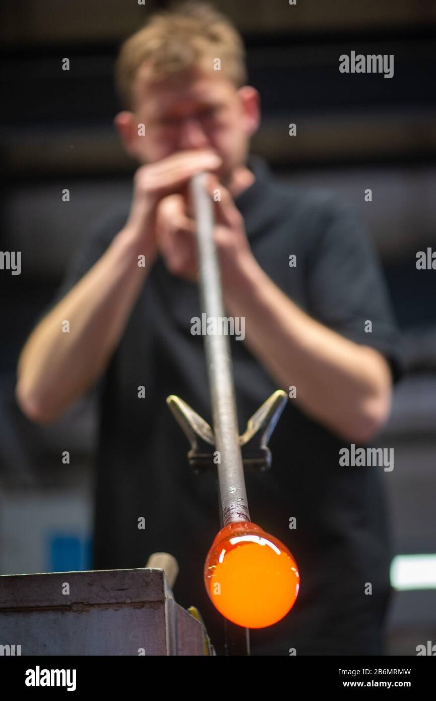 11 marzo 2020, Sassonia-Anhalt, Derenburg: Torsten Rötzsch, vetraio della fabbrica di vetro Harzkristall soffia attraverso un tubo in una sfera di vetro incandescente. Il vetro liquido viene utilizzato per creare un piatto che verrà premiato come trofeo del vincitore al Concorso Internazionale di Pianoforte "New Stars" il 4 aprile 2020 nelle Scuderie principesca di Wernigerode. I colori rosso e bianco si trovano nello stemma della città, sulle montagne di Harz. Il concorso di pianoforte inizia il 29 marzo 2020 e dura fino al 5 aprile 2020 ed è organizzato dalla città di Wernigerode e dall'Associazione degli amici Di Je Foto Stock