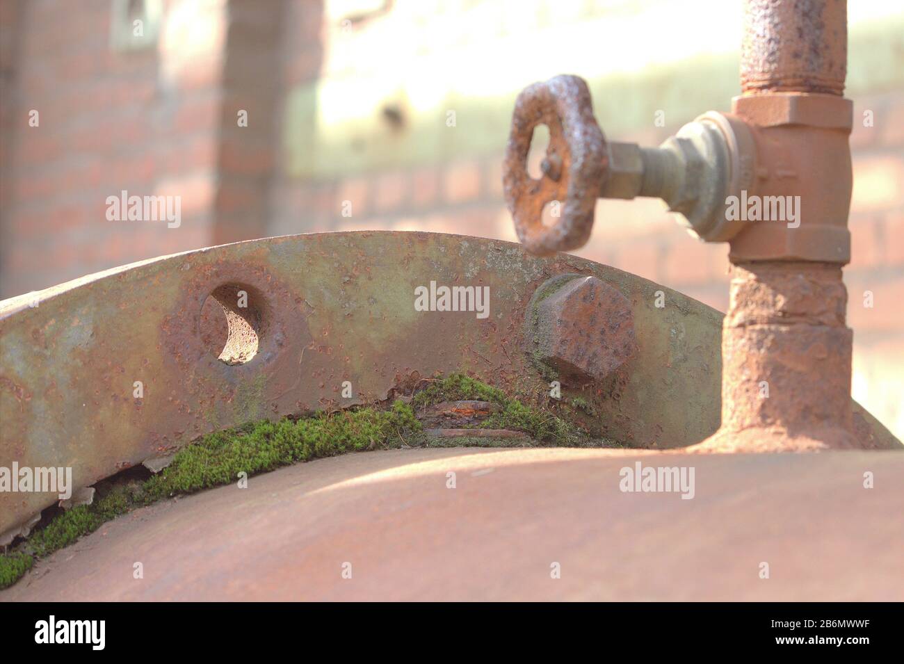 un grande tubo arrugginito coperto di muschio e una valvola di chiusura Foto Stock