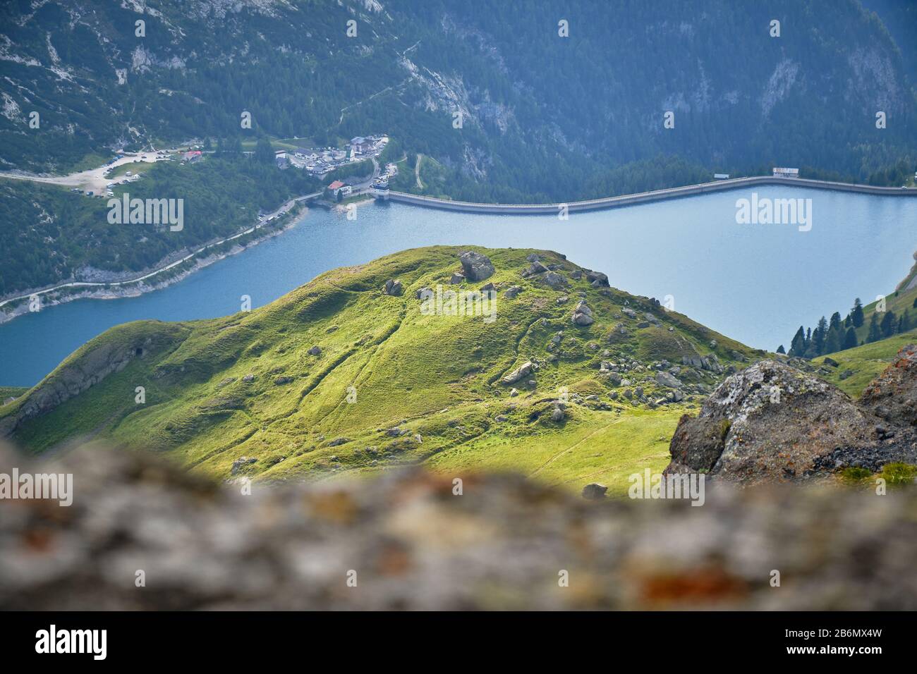 Patch di sole sulla collina verde sopra il lago Fedaia in montagna Dolomiti, Italia, come visto da un percorso di trekking sopra. Foto Stock