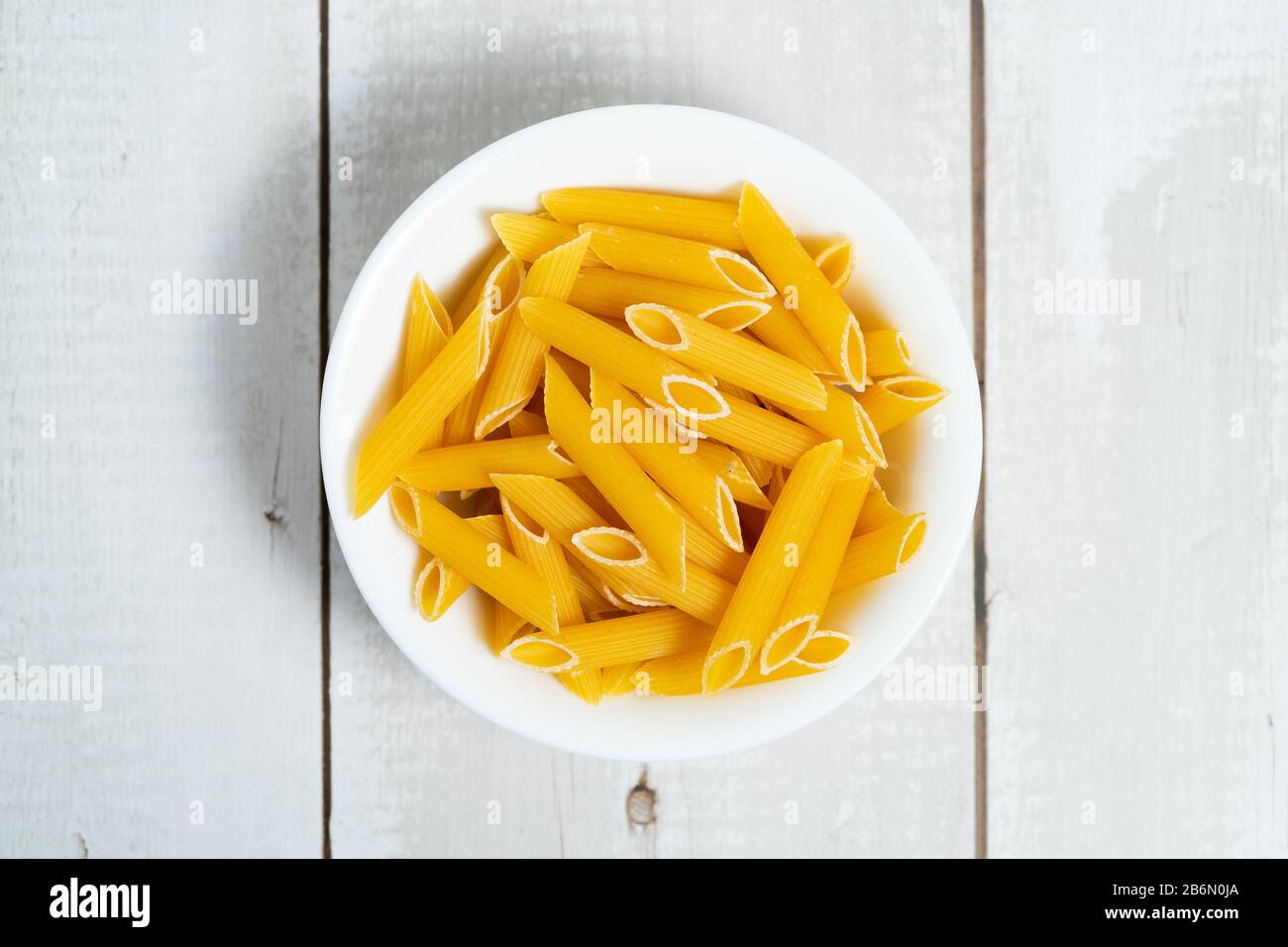 Ciotola di pasta cruda su tavola di legno Foto Stock