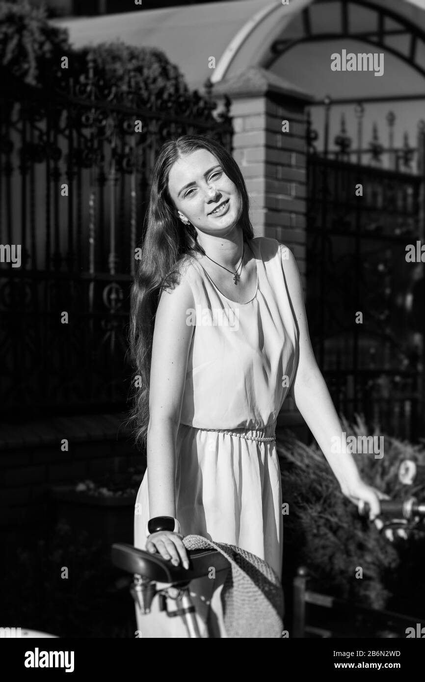 giovane donna capelli rossi con bici su strada guardando macchina fotografica sorridente, monocromatico Foto Stock