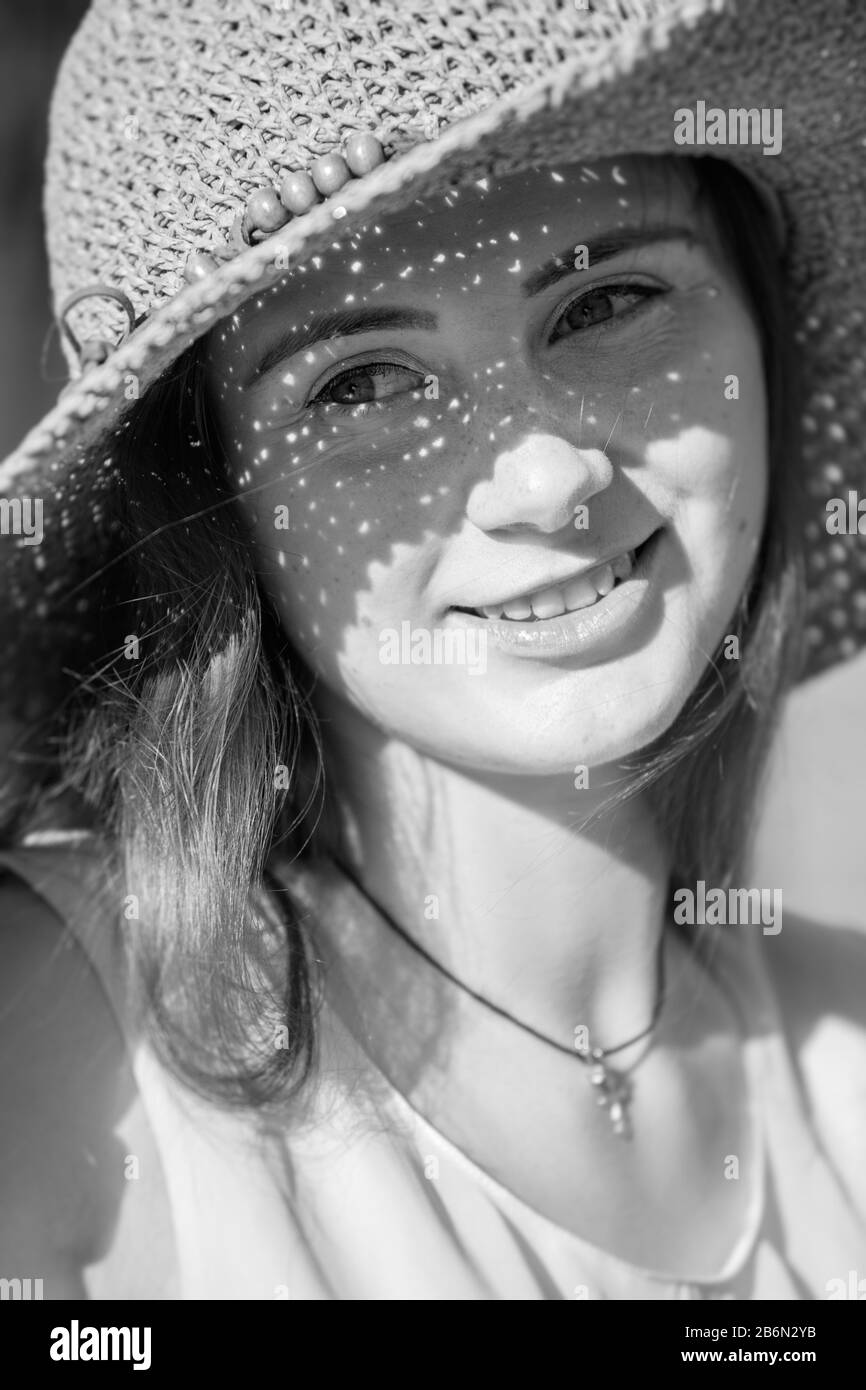 bella ragazza di capelli rossi in cappello da sole guardando da parte, sorridente, immagine monocromatica Foto Stock