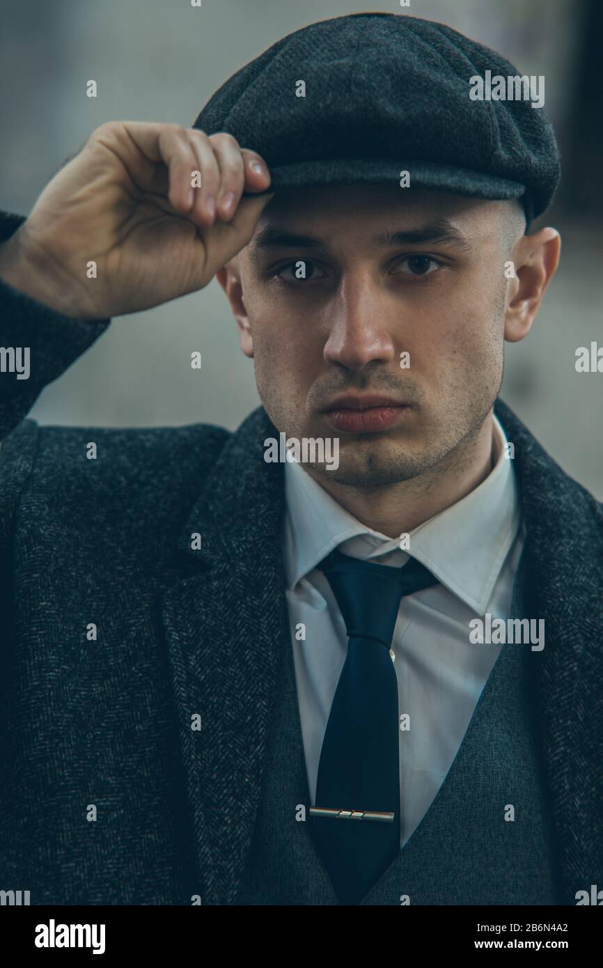 Ritratto di un uomo a immagine di un gangster retrò inglese della 1920s  vestito con un cappotto, un abito e una cuffia piatta in stile Spaky  blinders Foto stock - Alamy