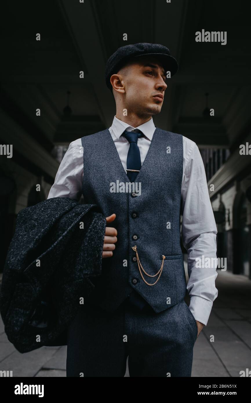 Un uomo che posa nell'immagine di un gangster retrò inglese della 1920s  vestito in Paky stile blinders alla strada della città Foto stock - Alamy