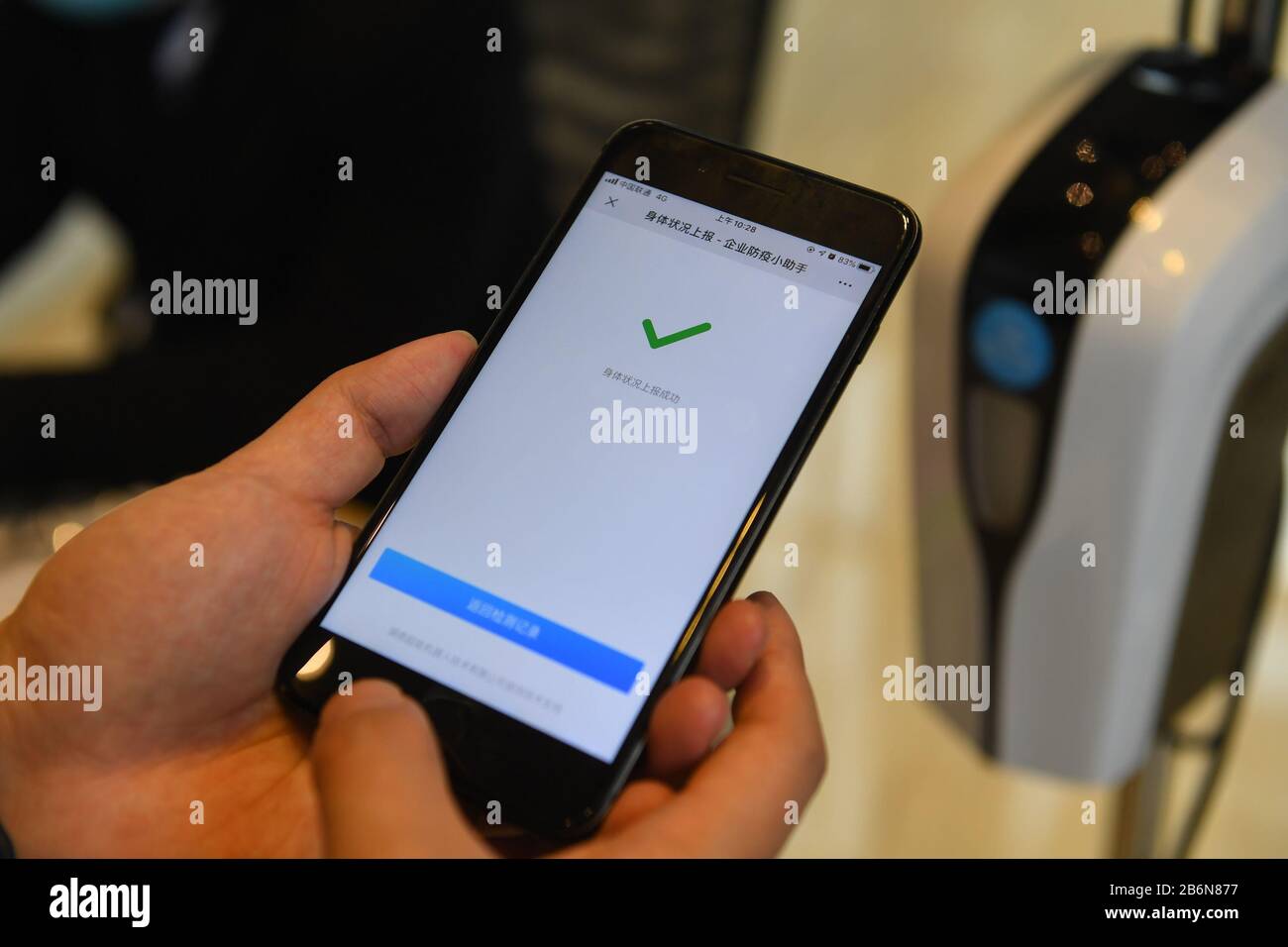 Changsha, Hunan, Cina. 11th Mar 2020. Un dipendente che ritorna al lavoro utilizza il robot di controllo mattutino per la nuova prevenzione dell'epidemia di coronavirus per testare la temperatura corporea e inviare i dati sanitari nel distretto di Kaifu di Changsha, nella provincia centrale cinese di Hunan, 11 marzo 2020. Le aziende tecnologiche del distretto di Kaifu di Changsha hanno progettato, adattato e creato robot di controllo del mattino per i nuovi sforzi di prevenzione dell'epidemia di coronavirus, che possono essere applicati e adattati alle diverse situazioni. Credito: Xinhua/Alamy Live News Foto Stock