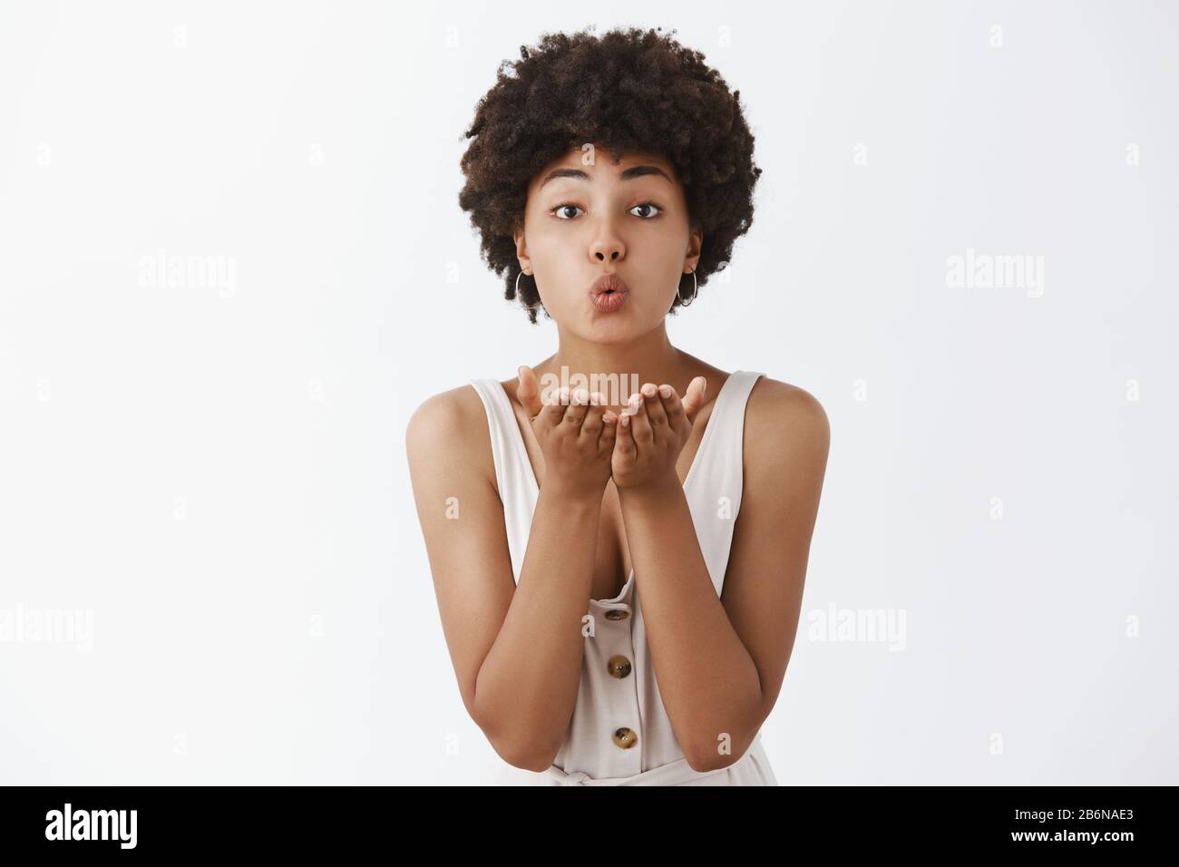 In attesa del vero amore a venire. Ritratto di tenera e carina donna afro-americana di charme con acconciatura riccia, labbra pieghevoli e tenere palme vicino Foto Stock