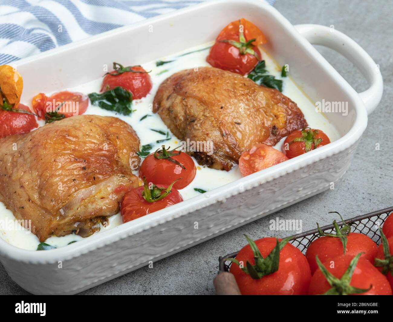 coscia di pollo cotta con spinaci cremosi e pomodori ciliegini Foto Stock