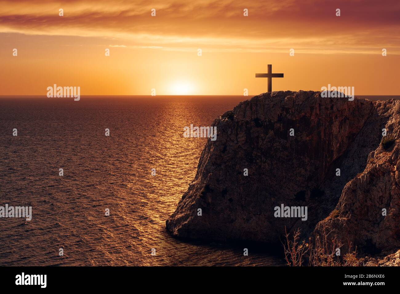 Veduta aerea di una crocifiga sul bordo di una scogliera contro il mare e il tramonto Foto Stock