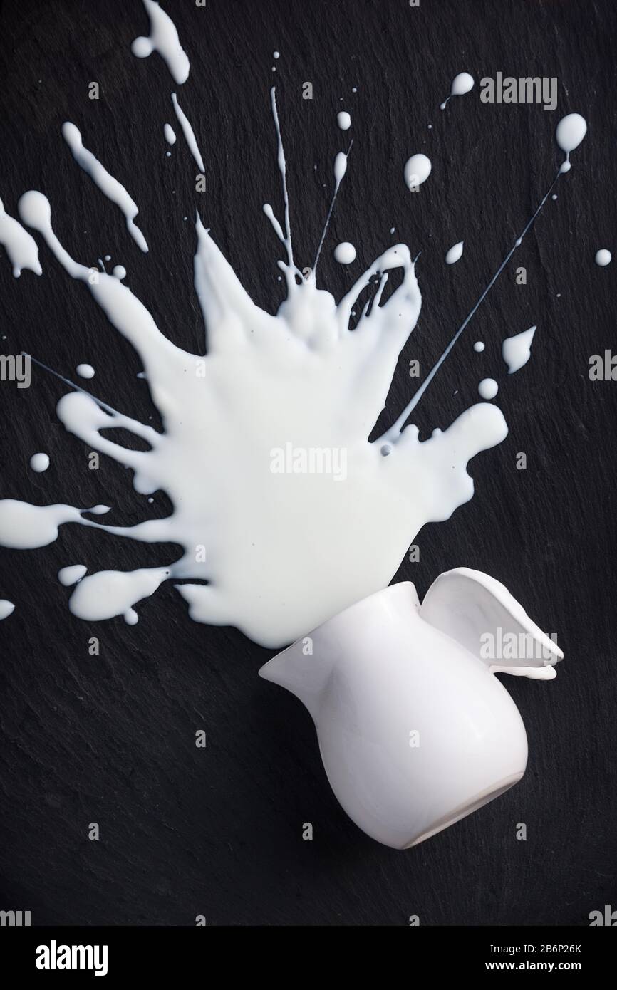 il latte bianco schizza a pezzi, isolato su sfondo nero, nessuno Foto Stock