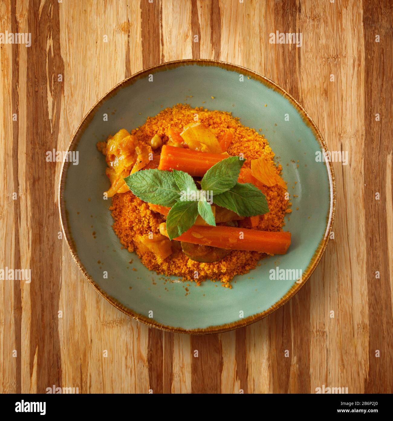 cibo marocchino, piatto cous su un piatto con carota, decorato con menta su un tavolo di legno e copia spazio per il testo Foto Stock