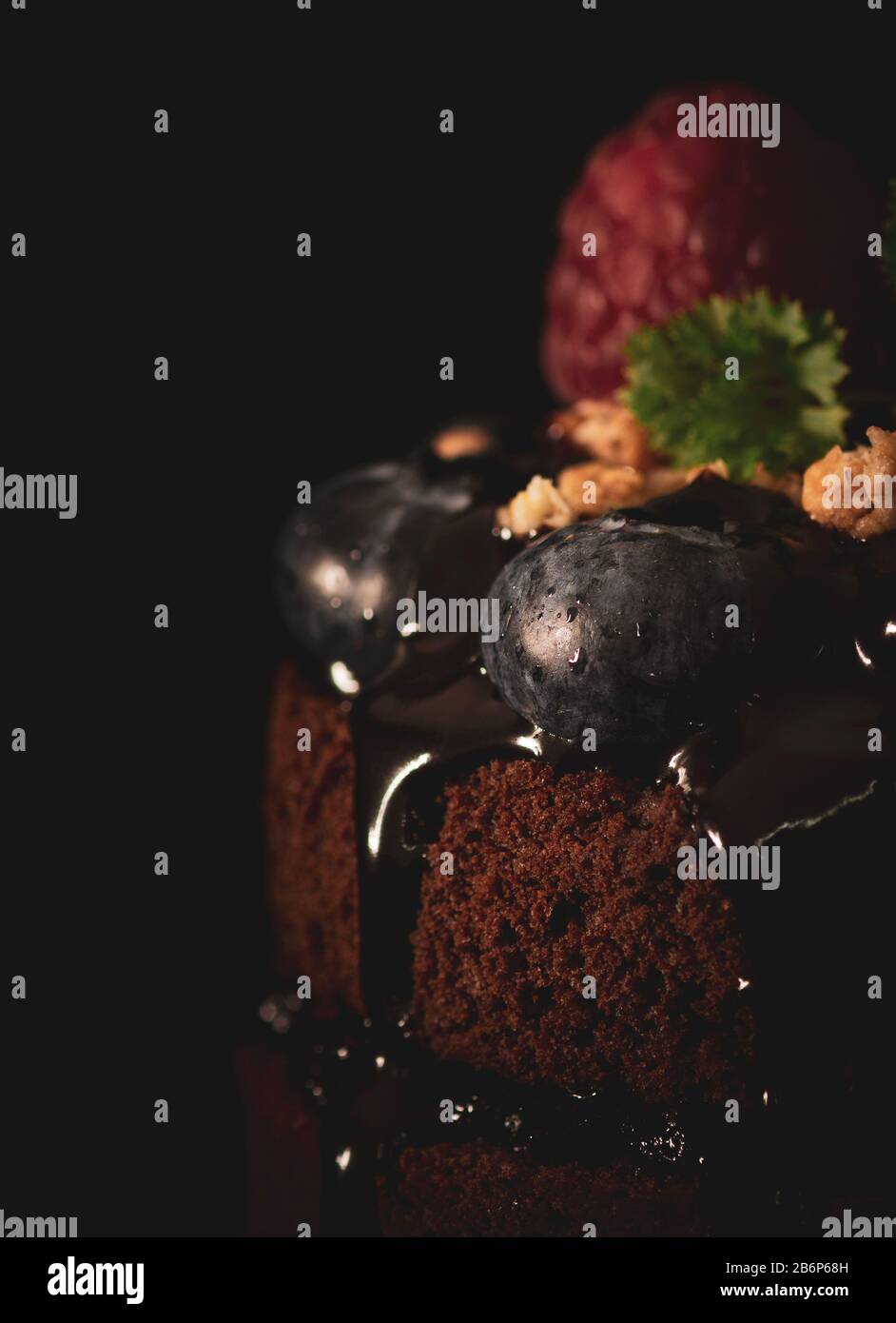Muffin al cioccolato con mirtilli su sfondo nero, stile Moody, foto di cibo con colori scuri, vista frontale, primo piano Foto Stock
