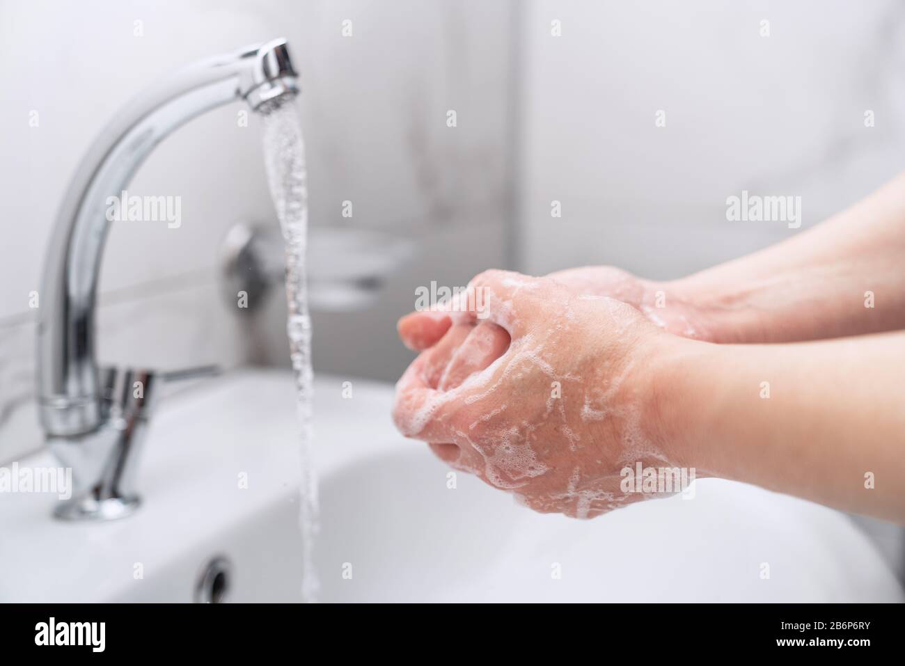 donna che pulisce le sue mani con sapone sul rubinetto per proteggere dal virus Foto Stock