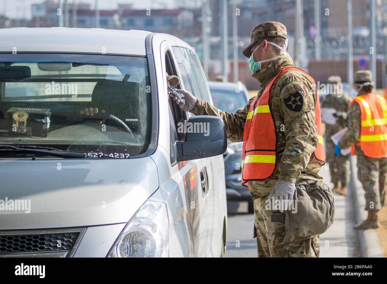 Soldato che prende la temperatura di un commuter per lo screening di COVID-19 presso la Garrison Humphreys (Camp Humphreys) dell'esercito degli Stati Uniti, Corea del Sud, 27 febbraio 2020. Foto Stock