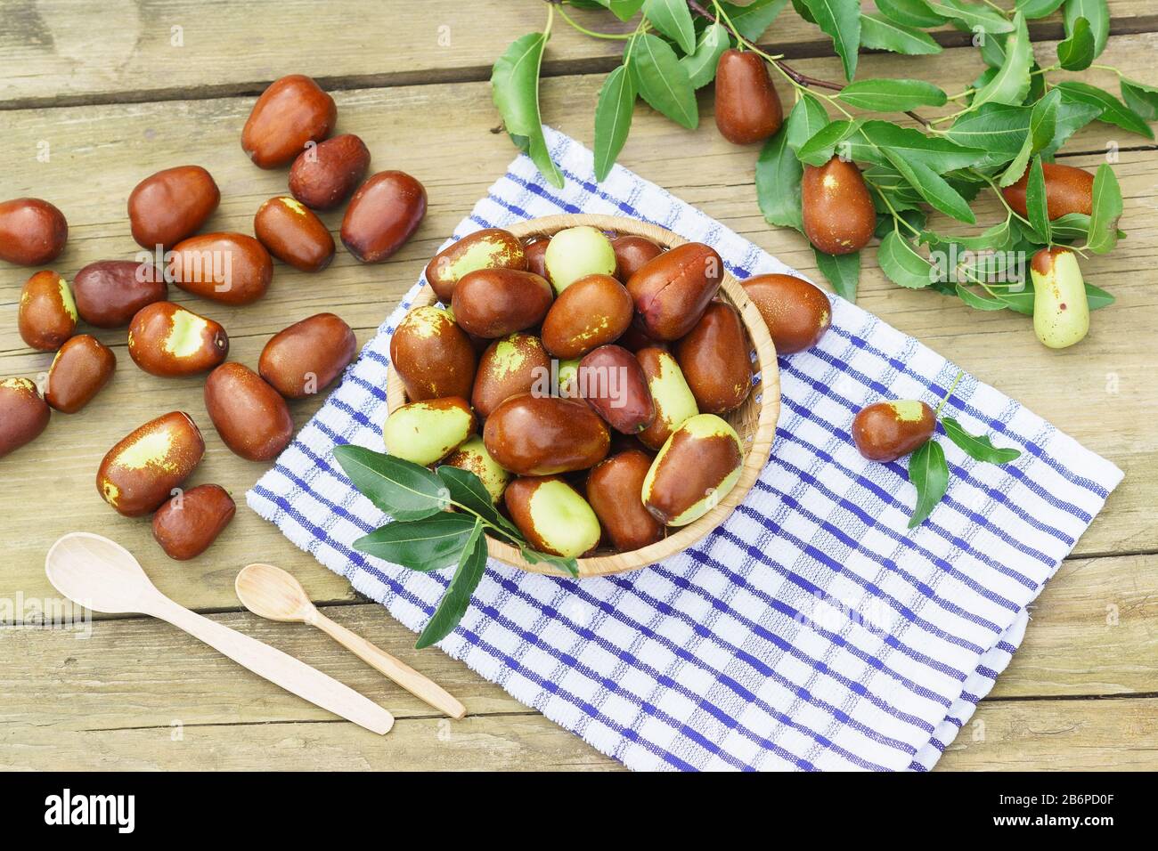 Cesto di vimini con frutta Ziziphus real, capiente, jujube, data cinese, capiinit, jojoba, cinese-date (lat.Ziziphus jujuba) e cucchiai di legno su un n Foto Stock