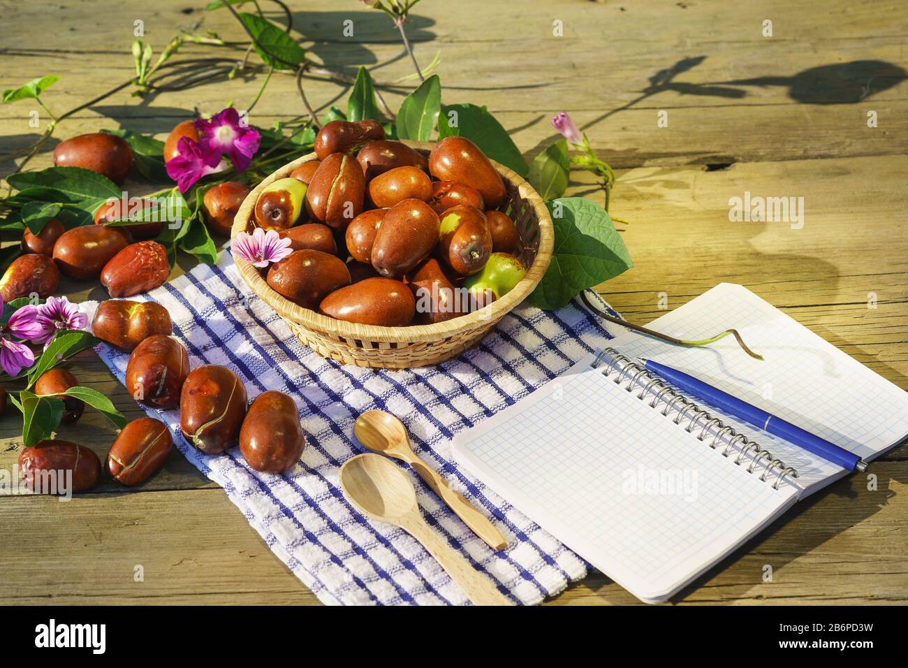 Cesto di vimini con frutti di Ziziphus reali, ciottoli, unabi, capiente, marmellata, capiinit, jojoba, dade cinese e pad di scrittura. Autunno ancora vita wi Foto Stock