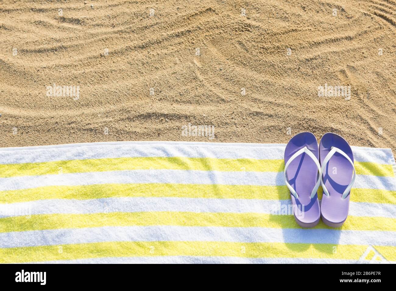 ciabatte viola su asciugamano giallo. Concetto di solarium sulla spiaggia Foto Stock