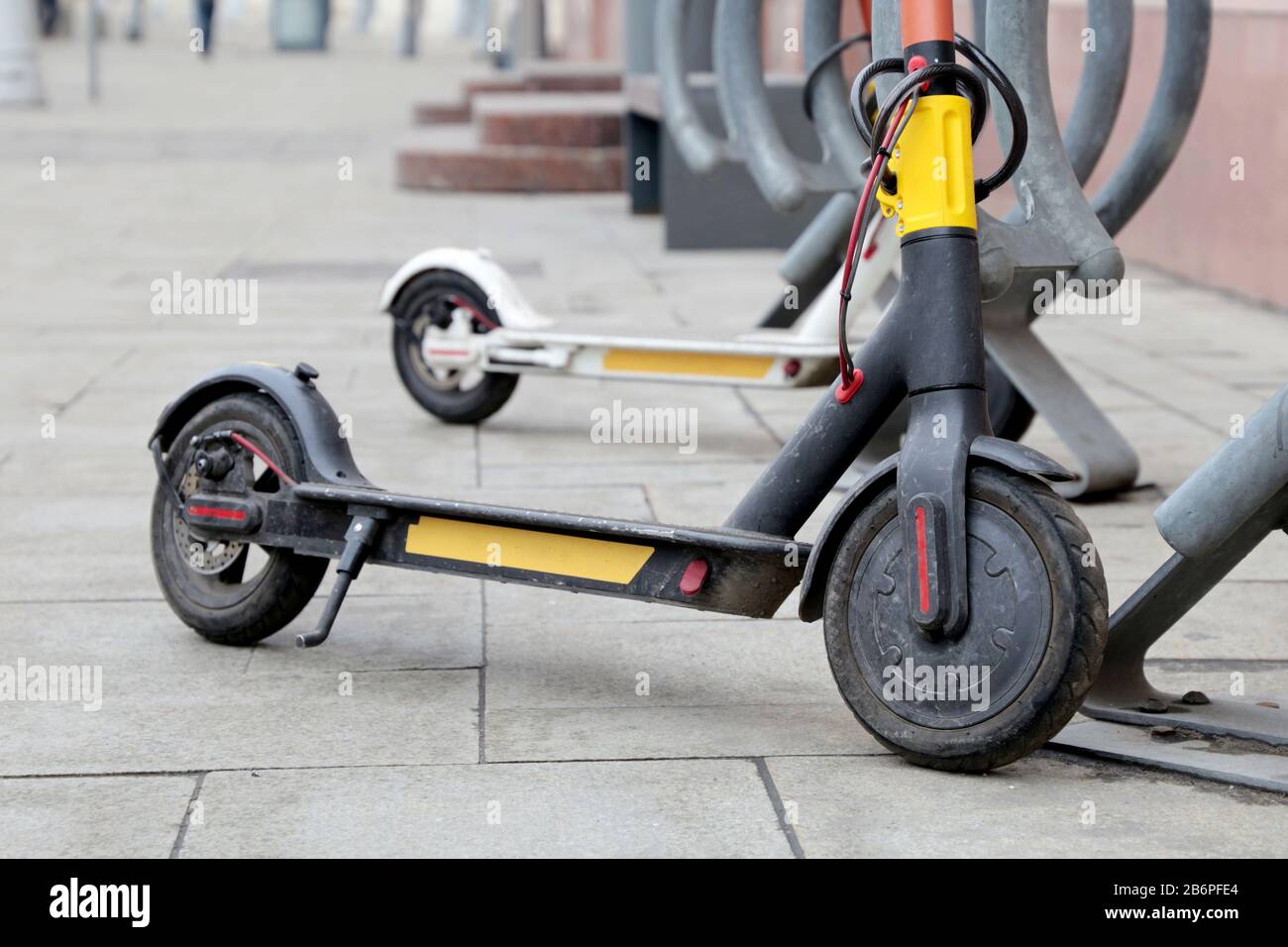 Scooters elettrici in una fila sul parcheggio. Noleggio bici da città, e-scooters pubblici sulla strada Foto Stock