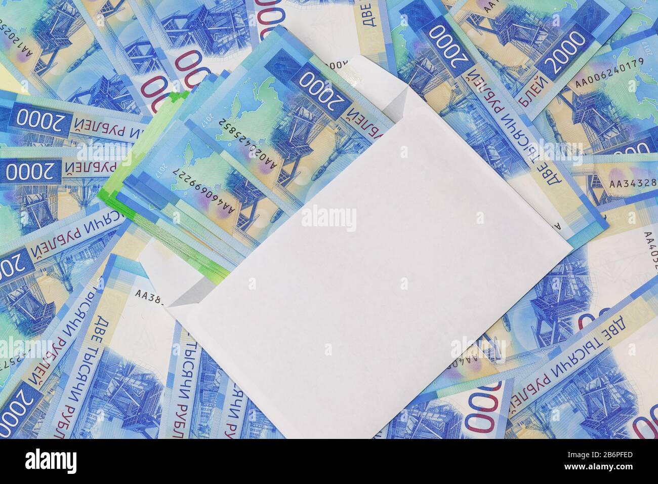 Busta bianca con denaro sullo sfondo delle nuove due millesimi fatture russe. La ricchezza come dono Foto Stock