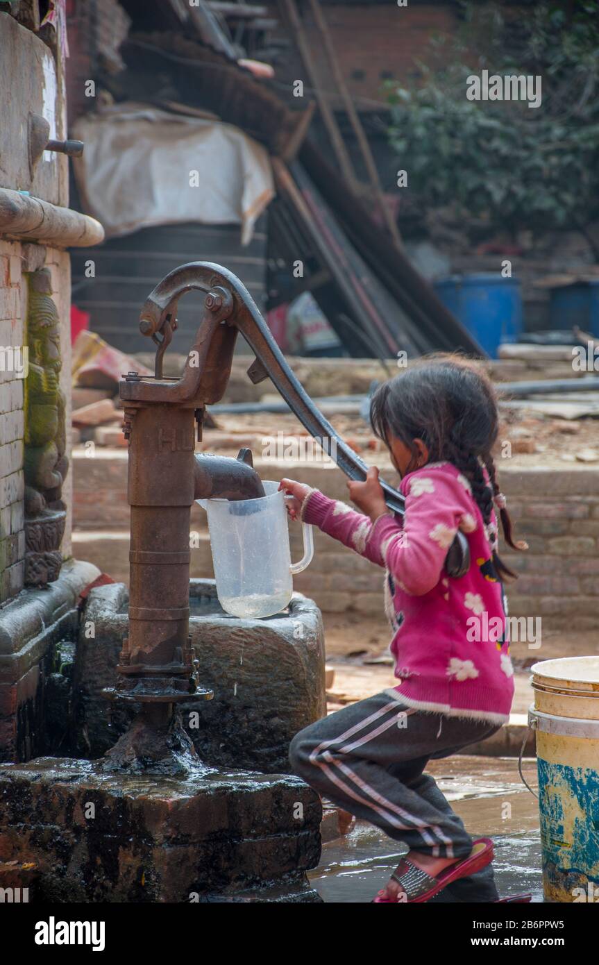 Bambina che ottiene l'acqua dalla pompa Foto Stock