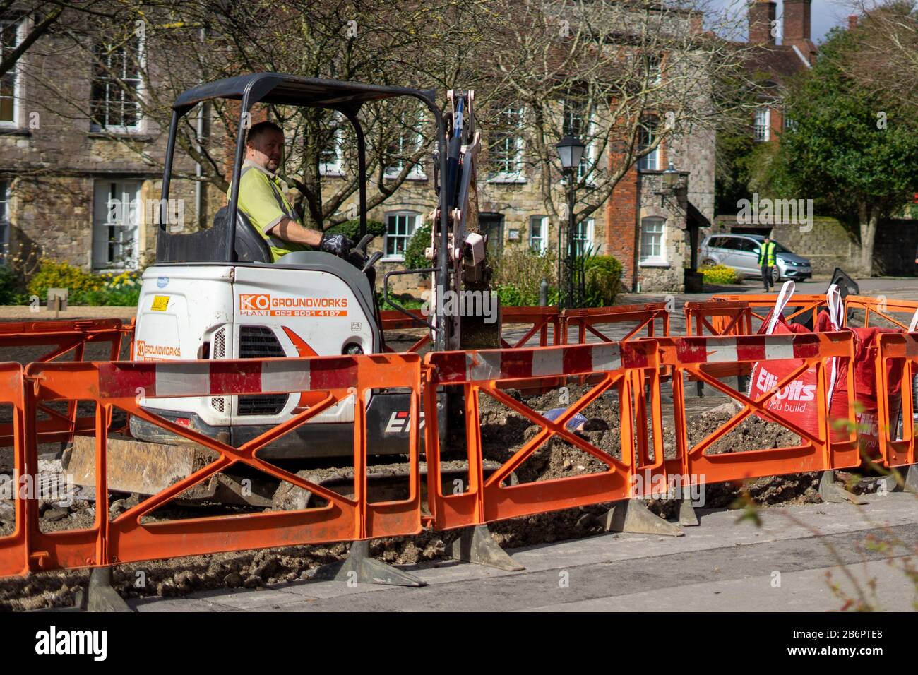 un costruttore o un lavoratore di costruzione seduto su un digger durante lavori di costruzione che scavano la strada Foto Stock