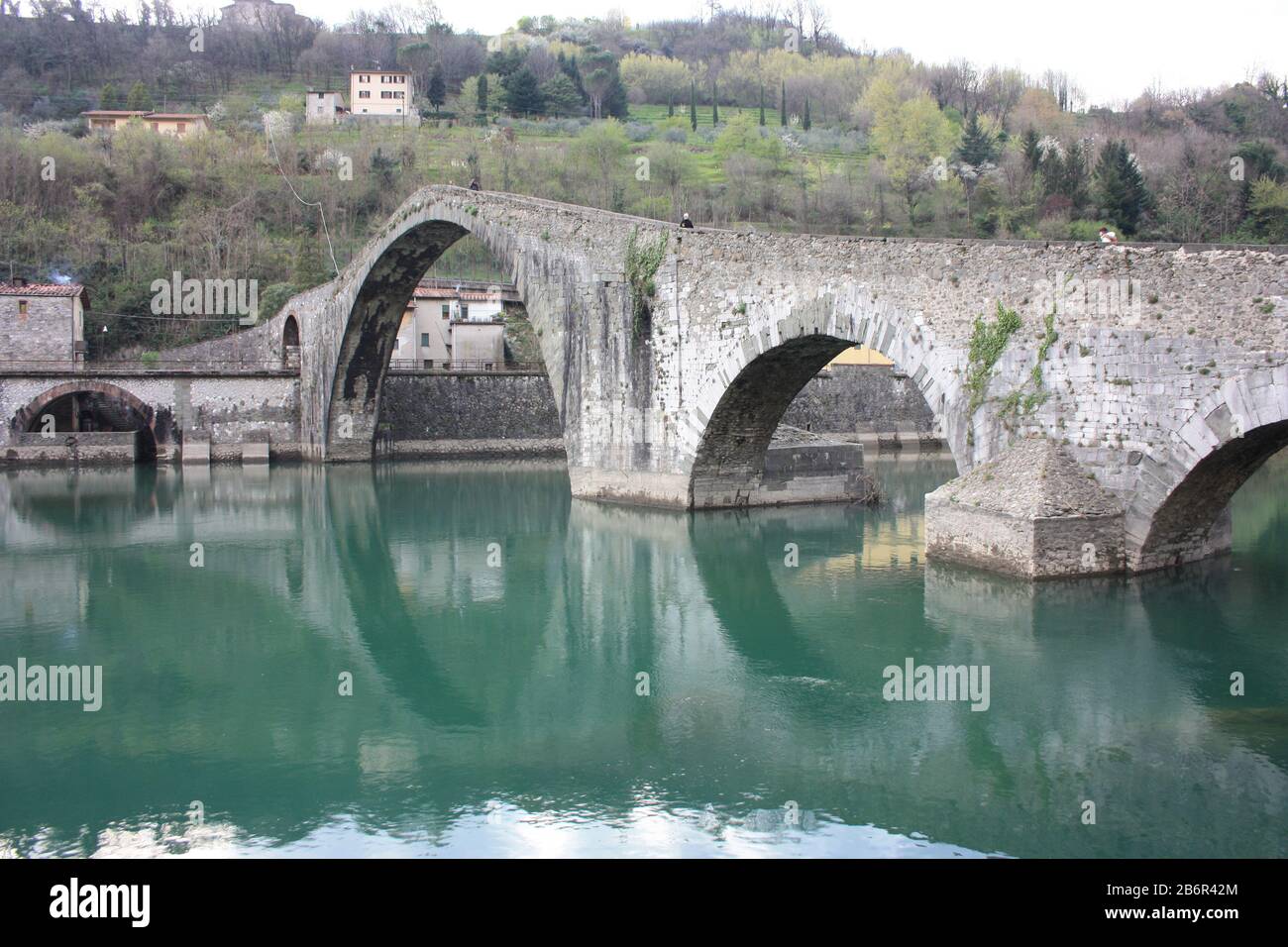 Il suggestivo e famoso Ponte della Maddalena di Lucca costruito in mattoni su un fiume in un antico borgo medievale di Borgo a Mozzano Foto Stock