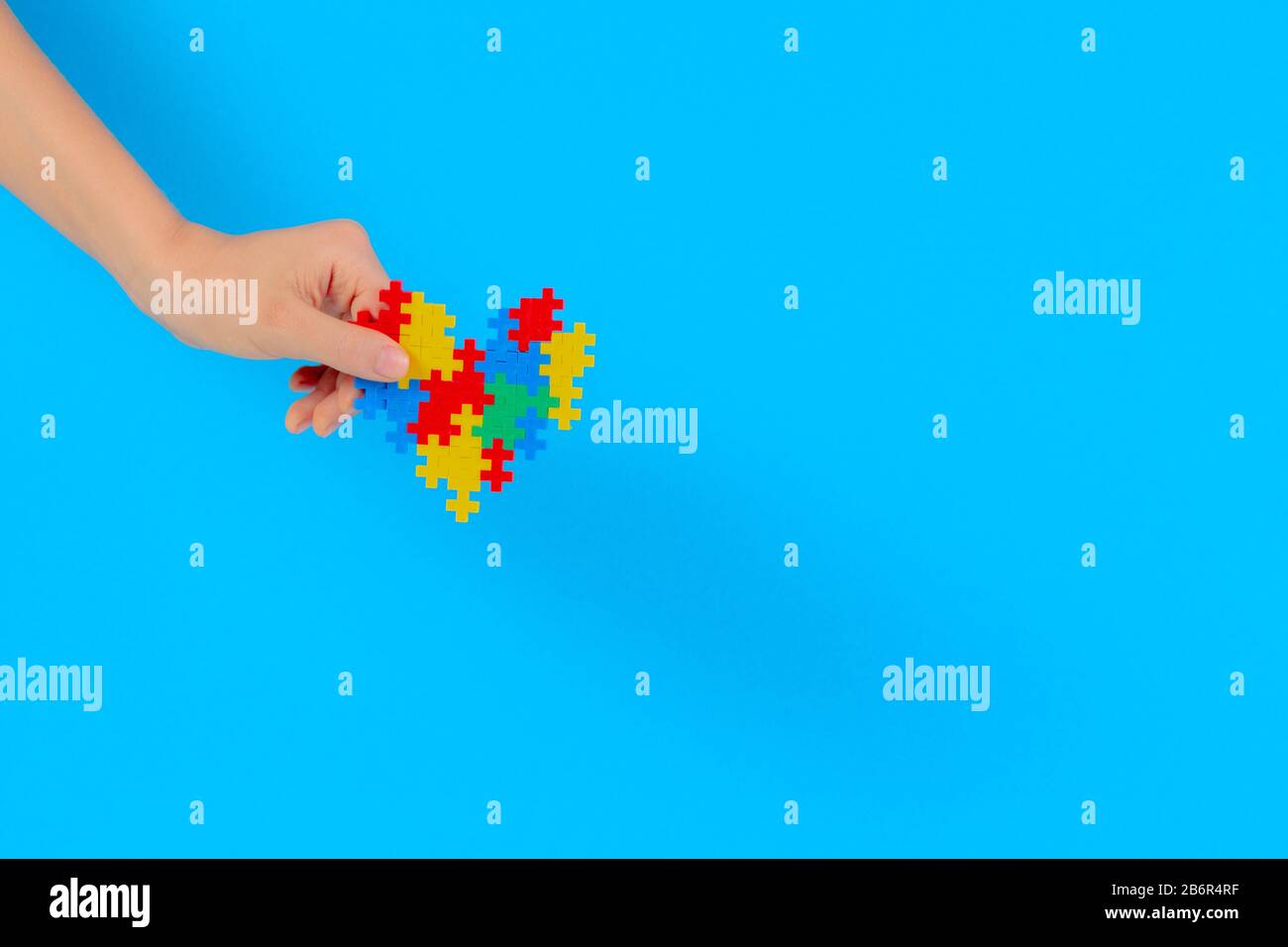 Bambino mano azienda cuore colorati su sfondo blu. Mondo autismo consapevolezza giorno di concetto Foto Stock