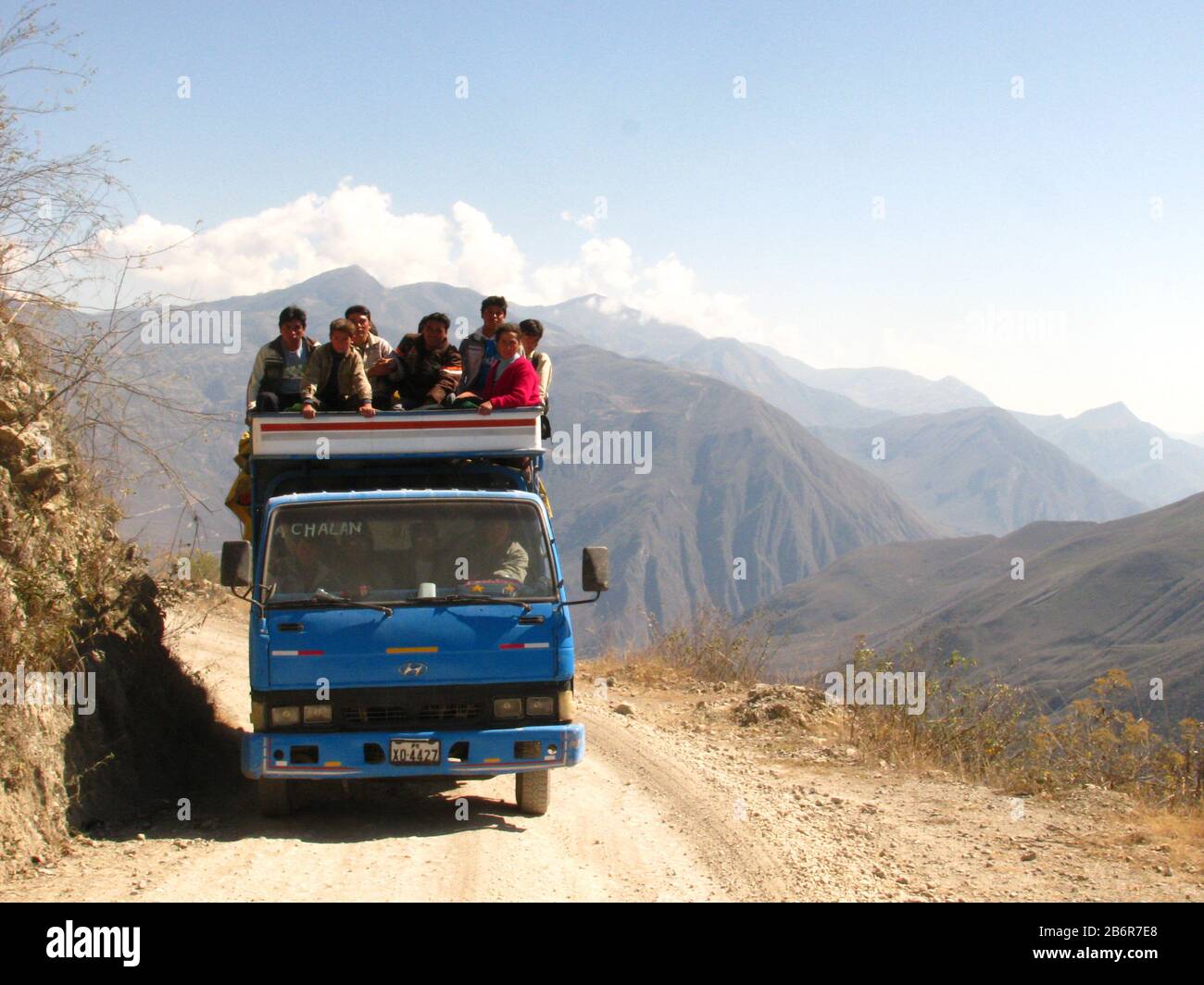 Celendin, Cajamarca, Perù. Gruppo di persone che si siede sopra un camion che guida su una strada sterrata per trasportarli. Montagne andine sullo sfondo Foto Stock