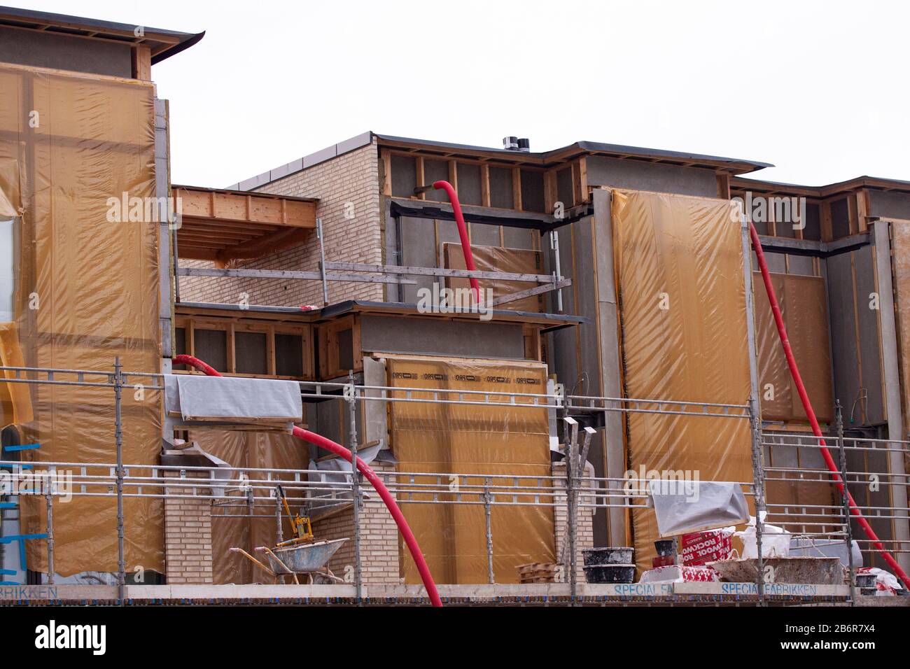 Nuovo basso edificio residenziale in costruzione con tubi rossi che si stacchino e finestre coperte: Copenhagen, 27 Febbraio - 2020. Foto Stock