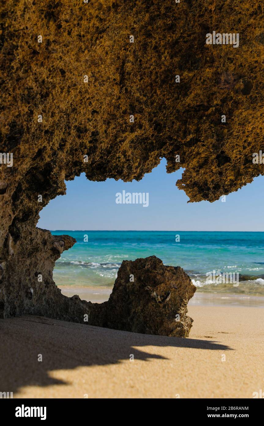 Vista attraverso una grotta di corallo su una spiaggia di sabbia sulla baia di Osprey nel Cape Range National Park nell'Australia Occidentale. Foto Stock