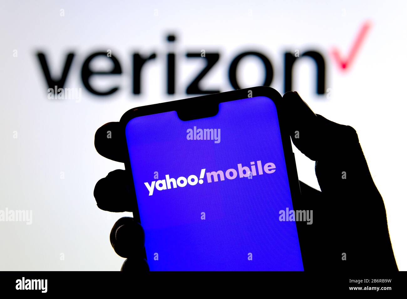 Stone / Regno Unito - 11 Marzo 2020: Yahoo! Logo mobile sulla silhouette dello smartphone tenere in mano e logo Verizon sullo sfondo sfocato. Foto Stock