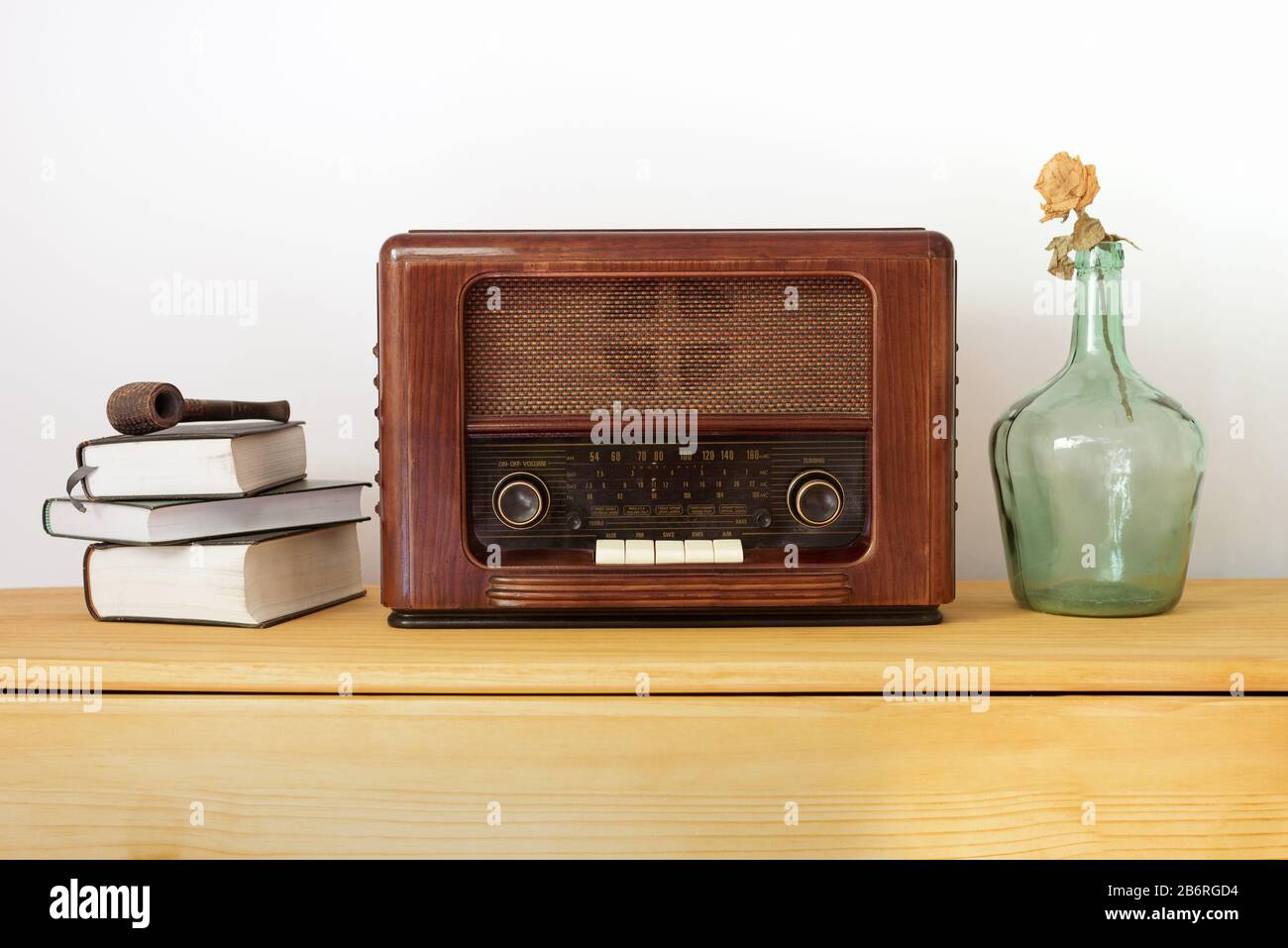 Radio d'epoca in legno, vecchi libri, vaso verde e una pipa su un tavolo Foto Stock