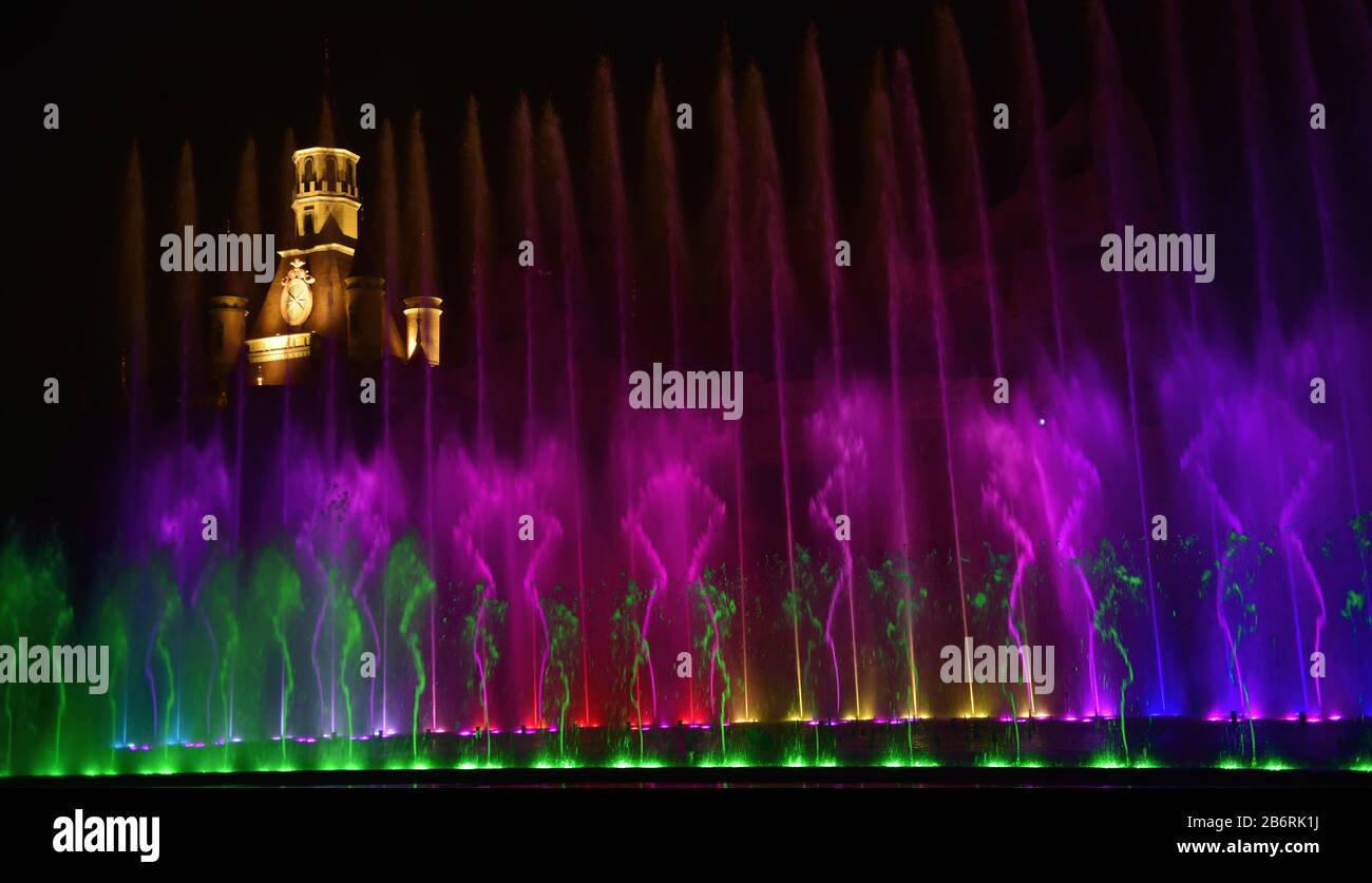 Bella fontana spettacolo. Grande spettacolo di fontana luminosa a getto d'acqua con danza decorativa multicolore di notte. Sfondo scuro. Foto Stock