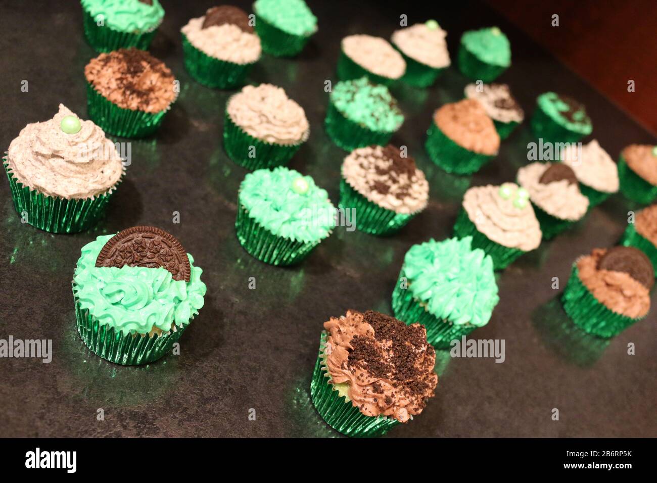 Grande gruppo di Cupcake verdi Decorati per compleanno o evento con biscotti sbriciolati e glassa Foto Stock