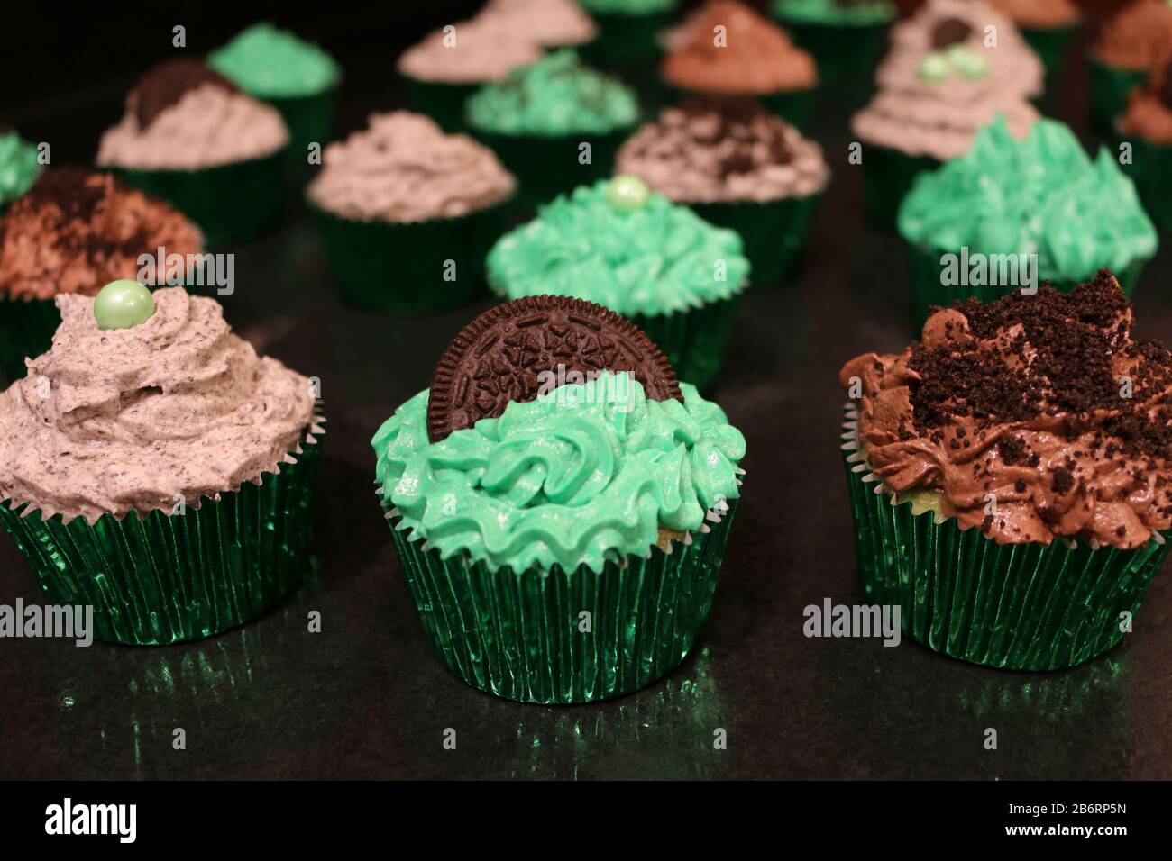 Tre Cupcake verdi Decorati per compleanno o evento con biscotti sbriciolati e glassa Foto Stock