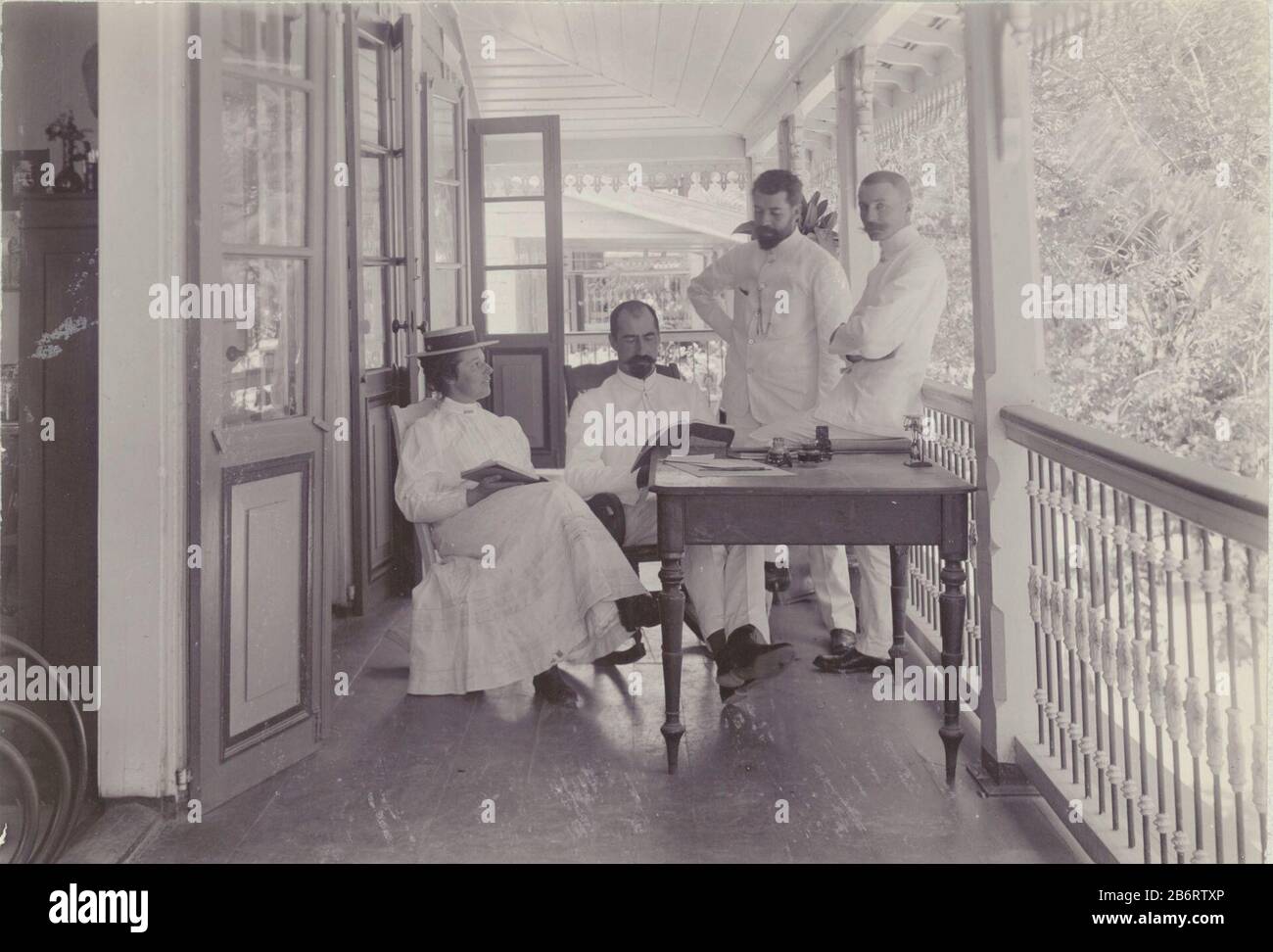 Groepsfoto op de Veranda Foto di gruppo sul portico della casa del Dr. Hall in Gravenstraat: Mistress Young, MR. Delle Arti, Dr. Hall e Andrew Boom. Paramaribo Ottobre 1908. Parte dell'album Family Tree-Gonggrijp in Suriname e Curaçao. Produttore : fotografo: Andrew August Tree fotografo: Anonimo luogo produzione: Paramaribo Data: Oct 1908 Materiale: Carta Tecnica: Fotografia dimensioni: H 122 mm × W 171 mm Oggetto: Loggia, veranda, porchWanneer 1908 - 1908 Foto Stock