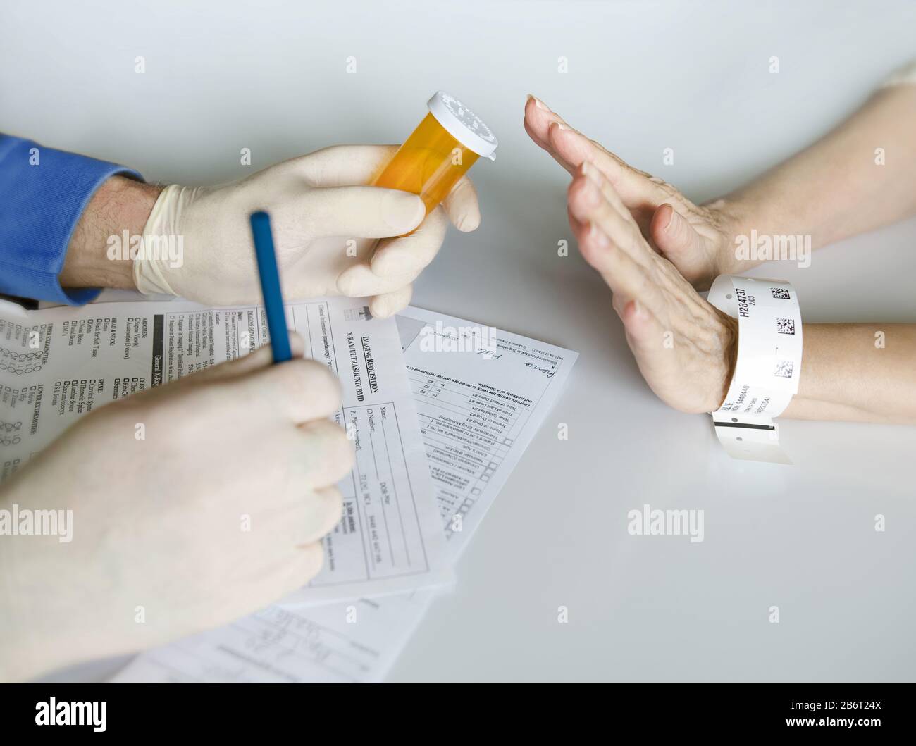 Le mani del medico davanti alle mani del paziente, mentre il paziente rifiuta i medicinali prescritti. Foto Stock