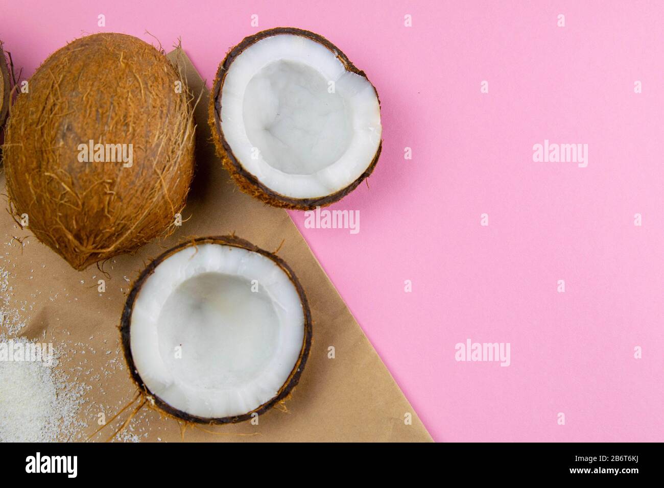 Noci di cocco rotte su carta artigianale, che si erge su uno sfondo rosa  Foto stock - Alamy