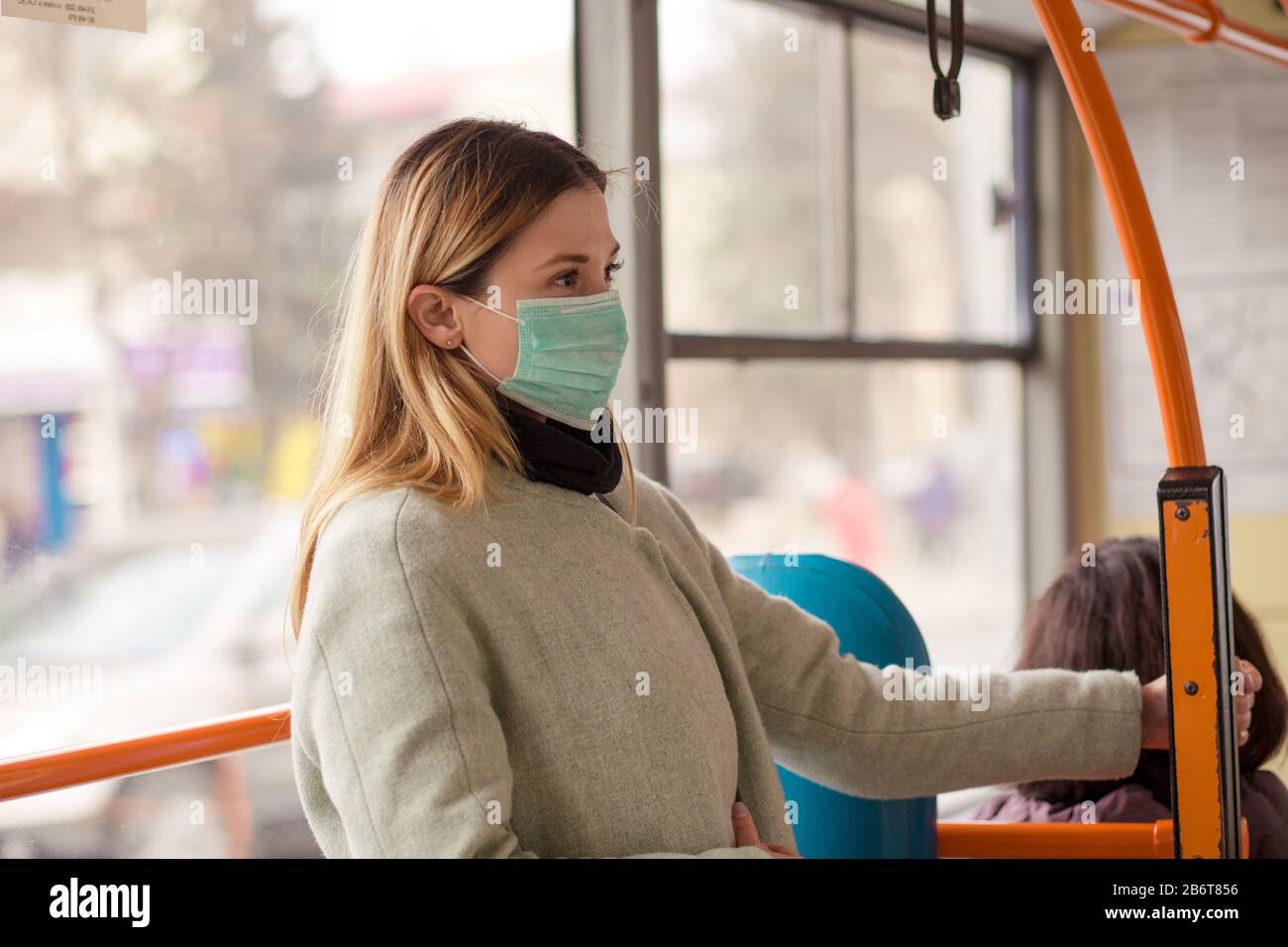 Donna che indossa una maschera medica protettiva sterile contro il coronavirus, il virus sars pandemico asiatico di Covid-2019 mentre si trova in un bus pubblico in un ci europeo Foto Stock