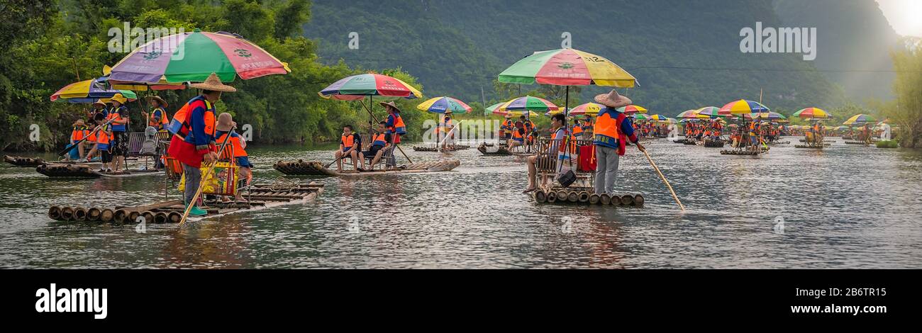 Yangshuo, Cina - Agosto 2019 : Vista panoramica dei turisti che galleggiano su zattere di bambù guidate da guide con lunghi bastoni su Yulo scenico e bello Foto Stock