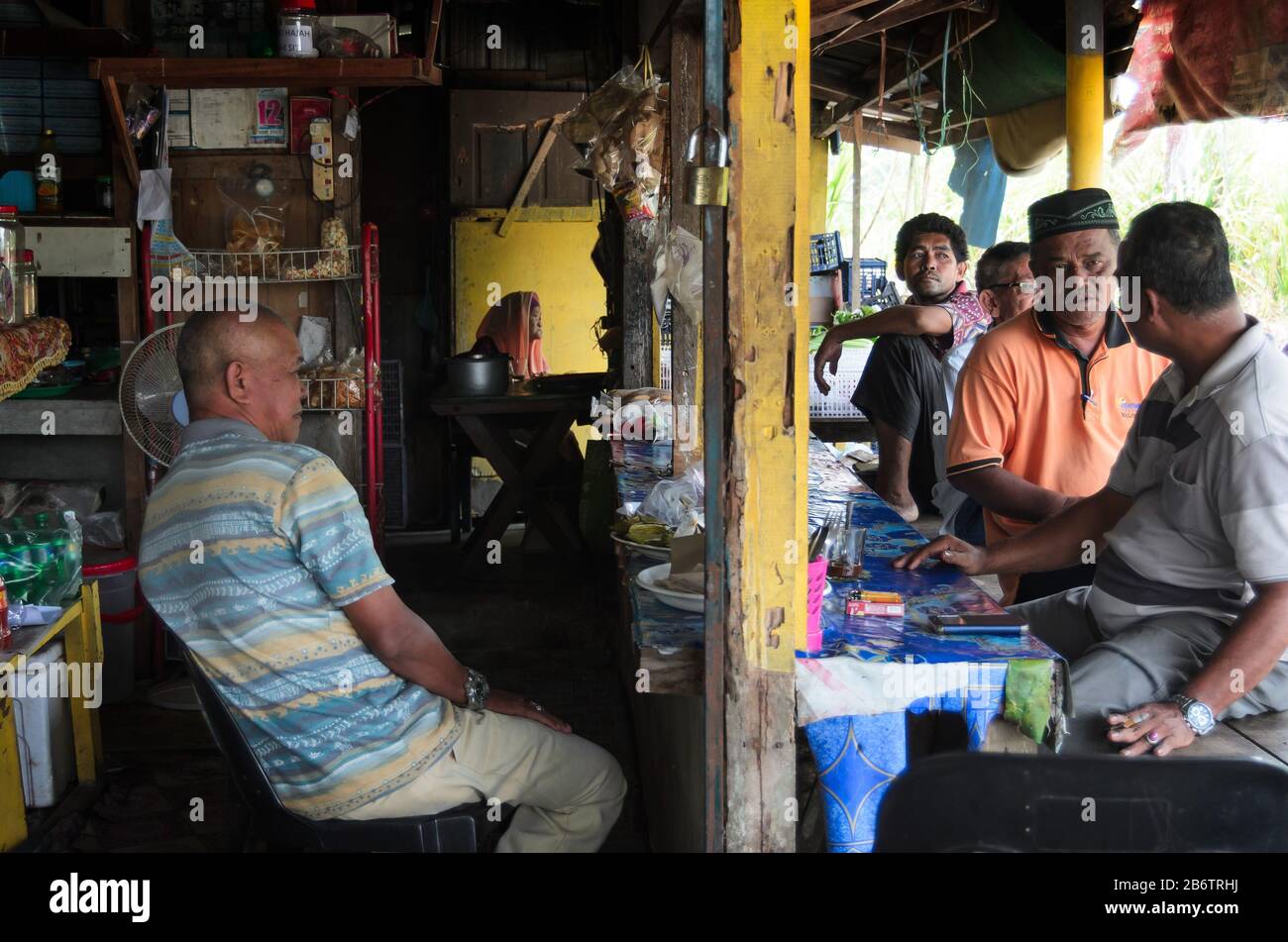 Uomini più anziani che appendono fuori in locale stalla (warung) bere il concetto di caffè in piccolo villaggio, Kelantan, Malesia. Foto Stock