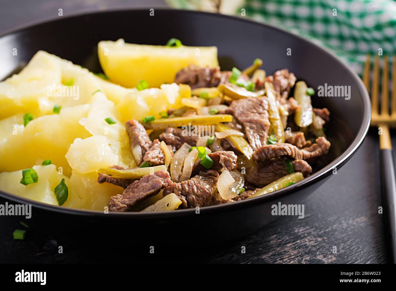Stufato di manzo, pezzi di manzo stufati con cetriolo decapato in stile russo. Stroganoff di manzo e patate bollite. Foto Stock