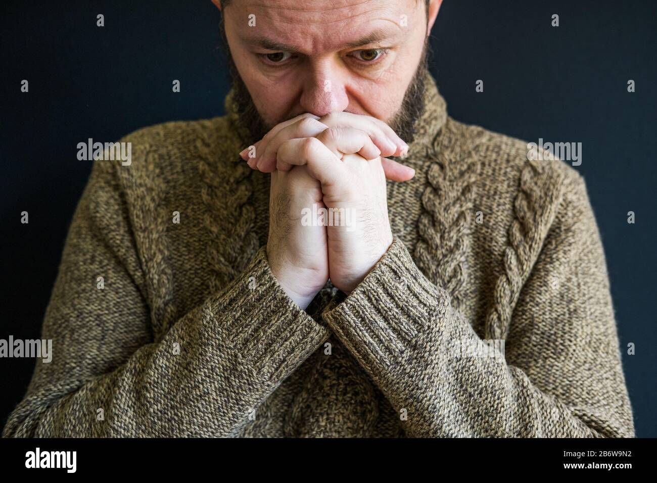 Infelice uomo in depressione, testa appoggiata su braccia incrociate Foto Stock