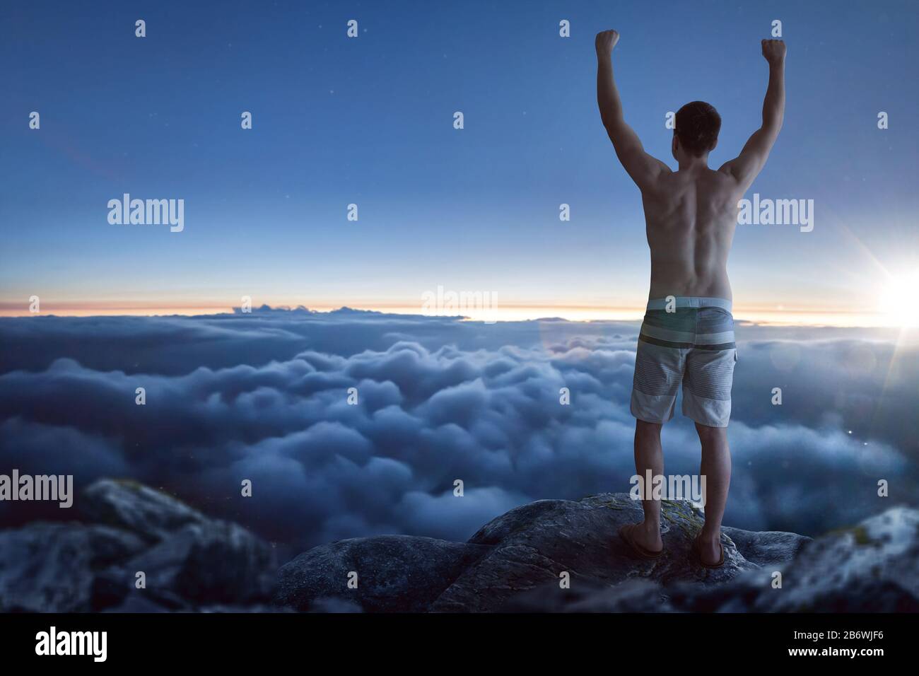 Uomo che si erge sopra le nuvole con braccia sollevate Foto Stock