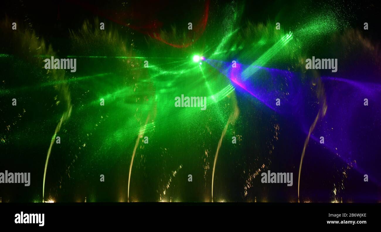 Fontane colorate. Bella laser e fontane spettacolo. Grande spettacolo di fontana luminosa a getto d'acqua con danza decorativa multicolore di notte. Scuro Foto Stock