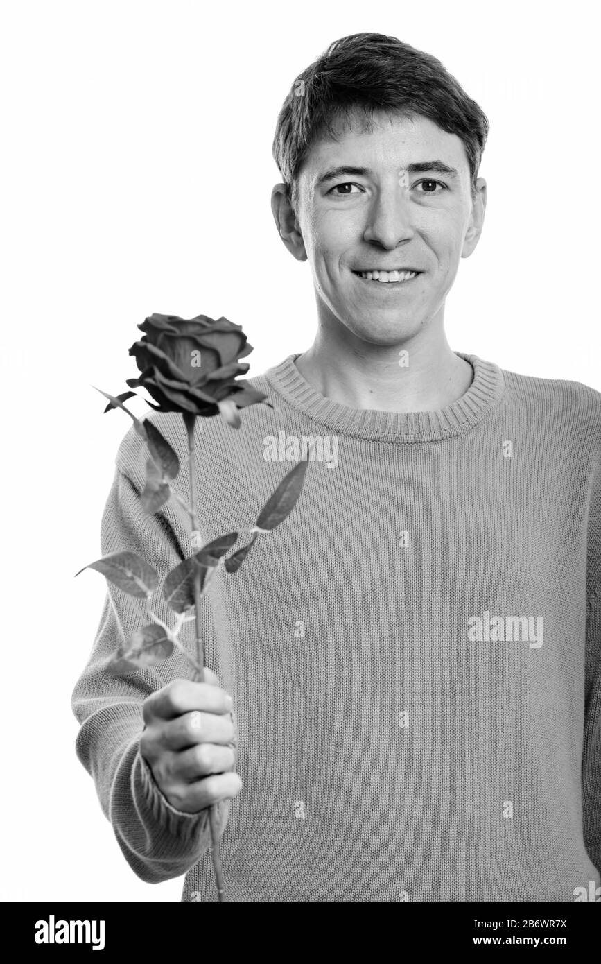 Studio shot di felice uomo sorridente mentre si tiene una rosa rossa Foto Stock