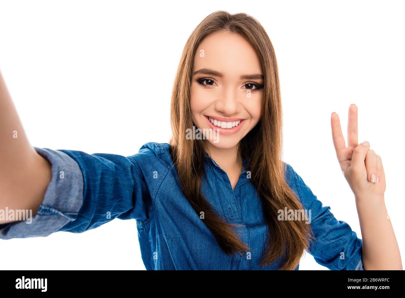 Bella donna sorridente facendo selfie e mostrando v-segno Foto Stock