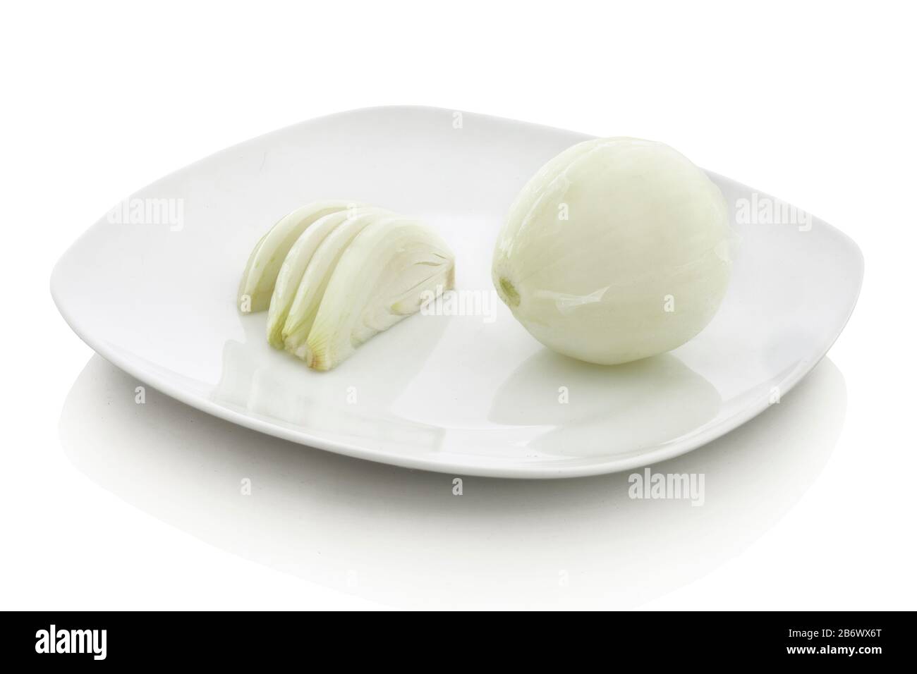 Cipolla intera e tagliata su piastra in ceramica bianca. Isolato su sfondo bianco con riflessione ombra. Con tracciato di ritaglio. Con percorso vettoriale. Un pezzo di Foto Stock
