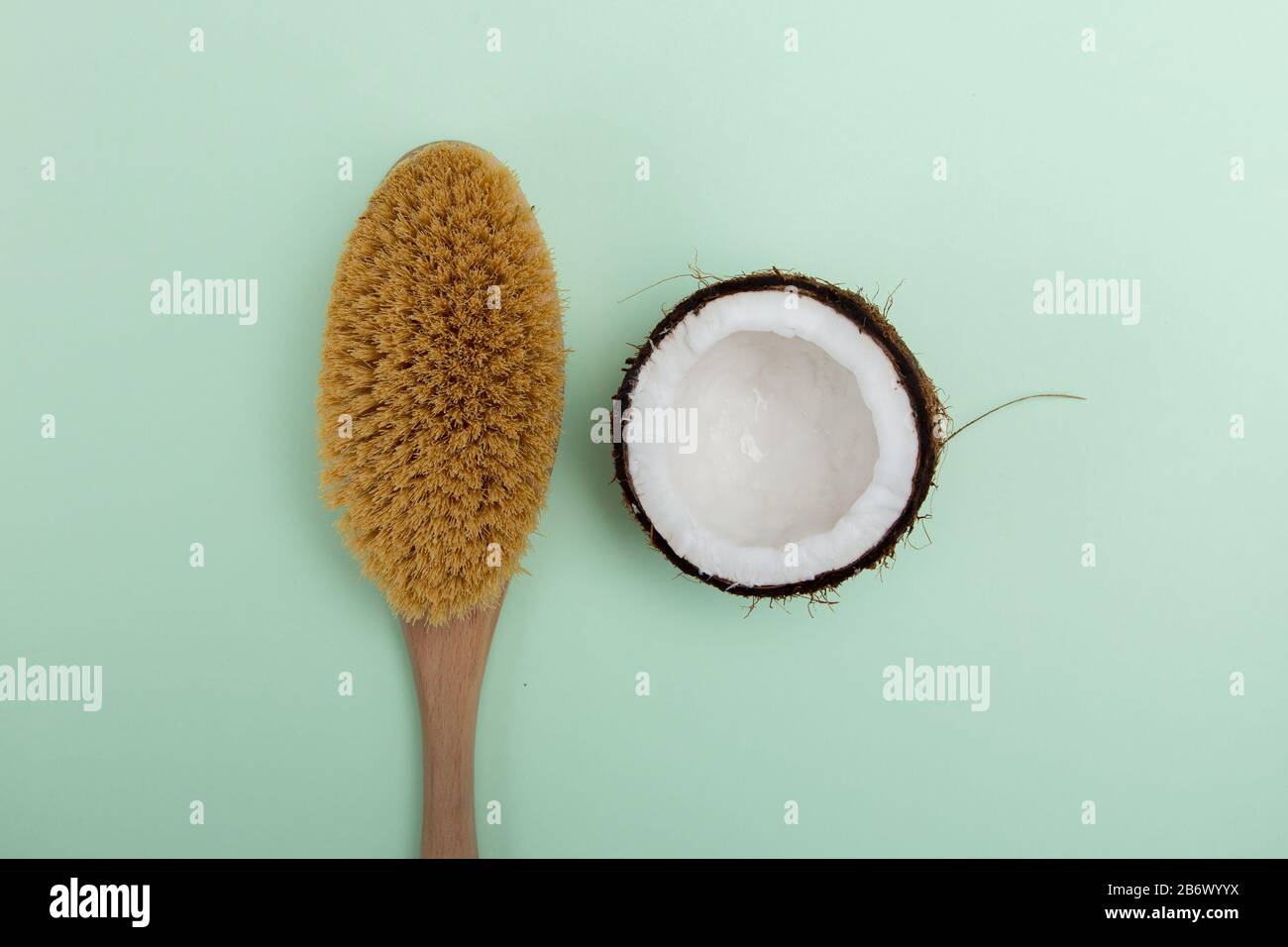 Spazzola massaggiante in legno e olio di cocco su sfondo blu. Il concetto di cura domestica della pelle. Foto Stock