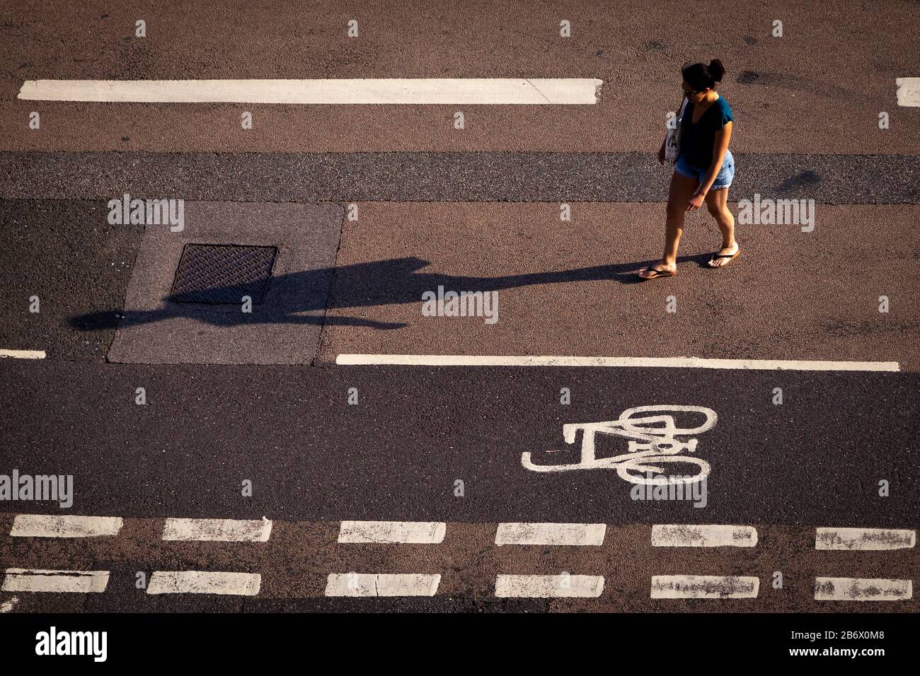 donna e le sue linee di attraversamento ombra sulla strada Foto Stock